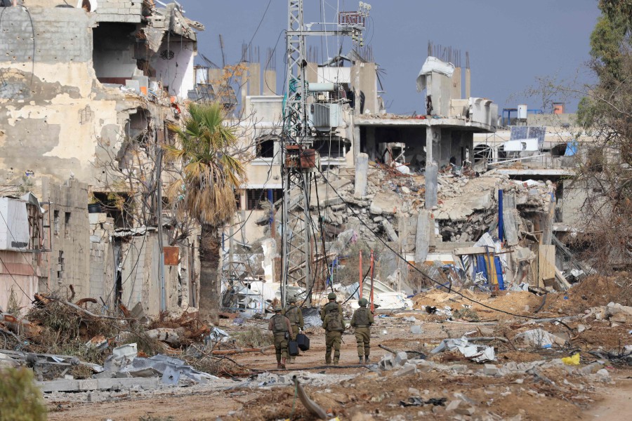 Israeli troops walk past destroyed buildings along the Salaheddine road which links the northern Gaza Strip with the south in the Zeitoun district on the outskirts of Gaza City on November 28, 2023. -AFP/MAHMUD HAMS