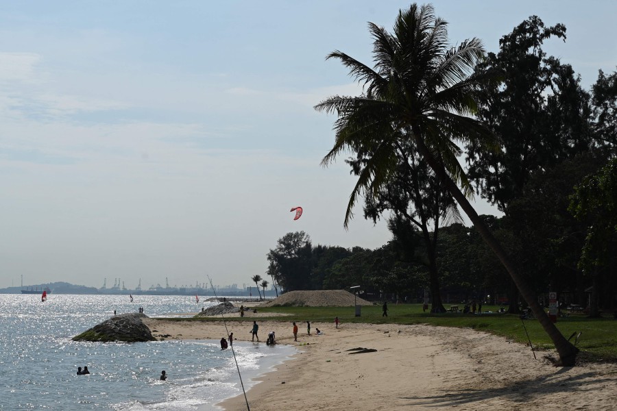 (FILE PHOTO) People relax at a beach at East Coast Park in Singapore. Singapore said November 28, 2023 it is considering building artificial islands off its east coast to protect low-lying areas against rising sea levels caused by climate change. -AFP/Roslan RAHMAN