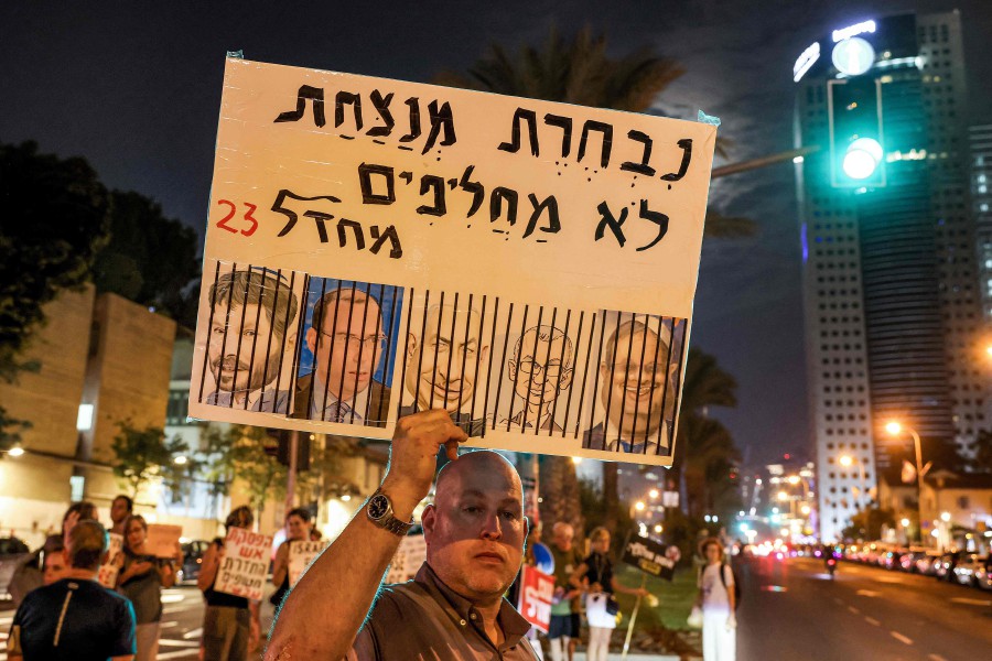 A man stands with a sign showing the faces of Israeli politicians (from left) Bezalel Smotrich (Finance Minister), Simcha Rothman (chair of the parliament's Constitution, Law and Justice Committee), Benjamin Netanyahu (Prime Minister), Yariv Levin (Justice Minister), and Itamar Ben-Gvir (National Security Minister) behind black bars, during a protest calling for the release of hostages in Tel Aviv. The families of the Israeli hostages demanded for an immediate government explanation about their fate after the army's intensified strikes, said the war cabinet had failed to explain to relatives whether the ground operation endangered the captives' well-being. -AFP/AHMAD GHARABLI