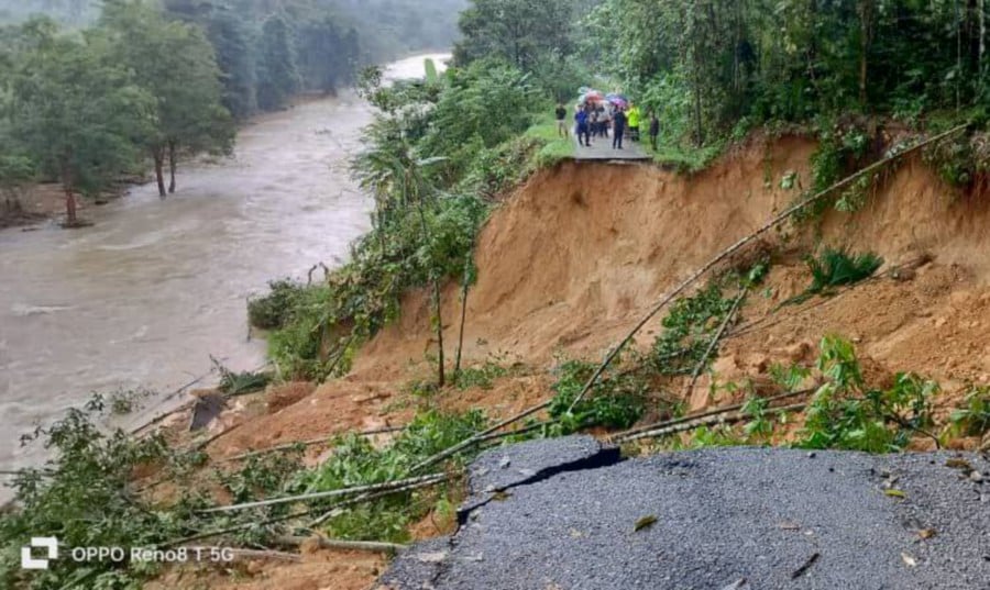 A 20m stretch of road in Kampung Seberang Janggut in Jeli, Kelantan had collapsed, leaving more than 200 residents stranded. -PIC COURTESY OF FIRE AND RESCUE DEPARTMENT