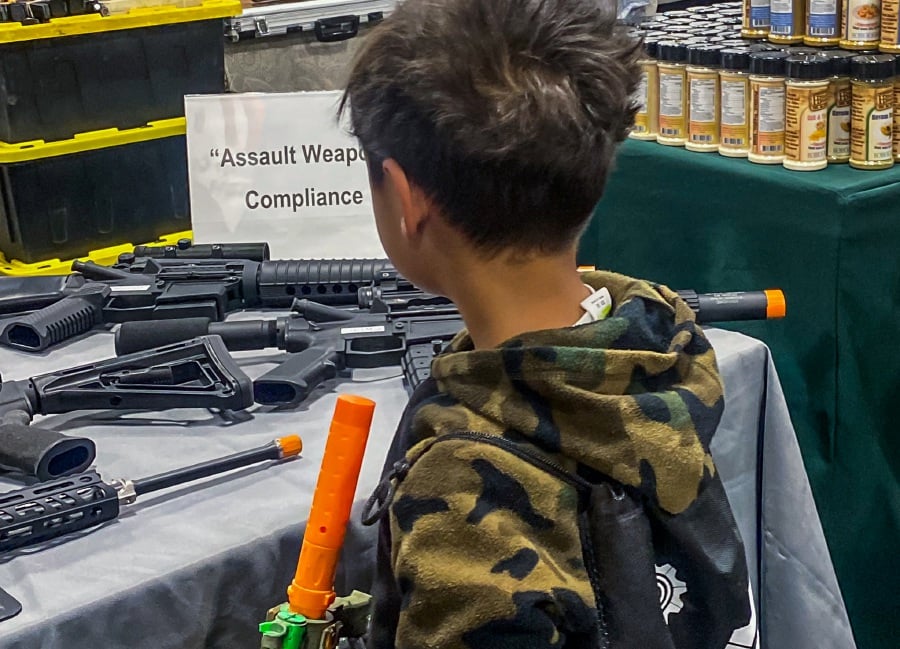 (FILE PHOTO) A boy holds an AR-15 toy gun while he looks at real assault weapons in a firearms shop booth at the Crossroads of the West Gun Show at the Convention Center in Ontario, California. A federal appeals court on Saturday cleared the way for a California law that bans the carrying of guns in most public places to take effect at the start of 2024, as the panel put on hold a judge's ruling declaring the measure unconstitutional. -AFP/Apu GOMES