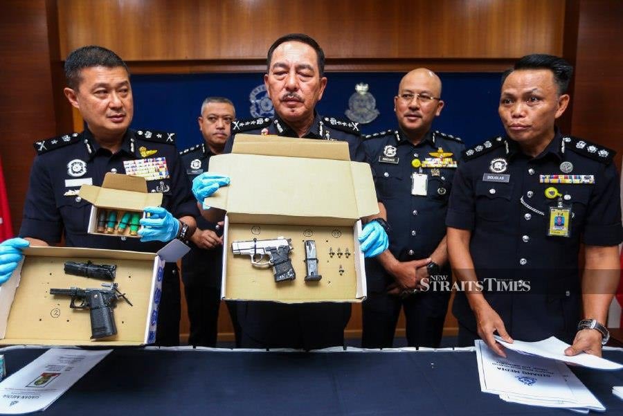 Kelantan police chief Datuk Muhamad Zaki Harun (centre) with his officers, showing the weapons and bullets seized, during a press conference at the state police headquarters. - NSTP/NIK ABDULLAH NIK OMAR