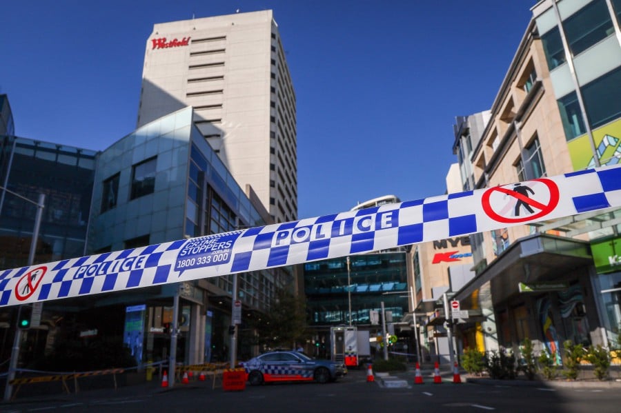 Police tape can be seen in front of a roadblock outside the Westfield Bondi Junction shopping mall in Sydney on April 14, 2024, the day after a 40-year-old knifeman with mental illness roamed the packed shopping centre killing six people and seriously wounding a dozen others. -- AFP