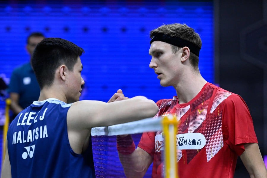 Malaysia's Lee Zii Jia (L) shakes hands with Denmark's Viktor Axelsen after the Danish shuttler retired during the men's singles quarter-final match against at the 2023 Sudirman Cup world badminton championships in Suzhou in China'. - AFP PIC