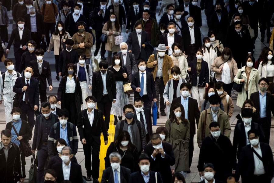 Commuters wearing face masks walk at Shinagawa Station in Tokyo. -AFP pic