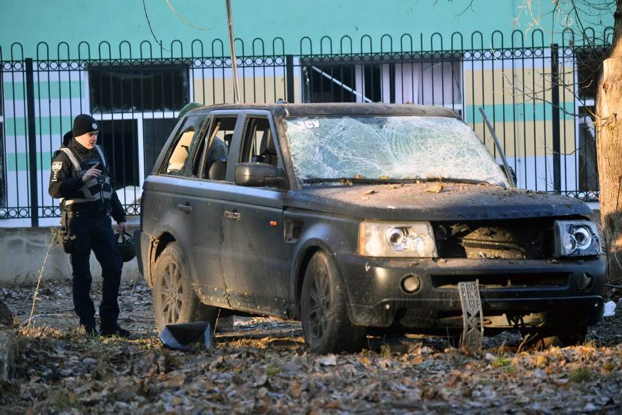 A Ukrainian policeman examines a car damaged in the explosion of a downed Russian drone in a yard in Kyiv on November 25, 2023, amid the Russian invasion of Ukraine. -- Pic: AFP