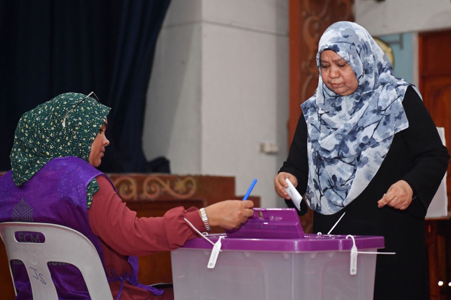 A voter (R) casts her ballot during the country's parliamentary election, in Male on April 21, 2024. -- AFP