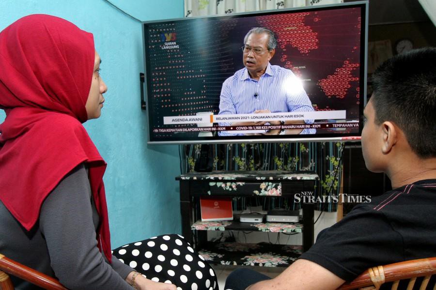 Housewife Siti Norhuda Salwa Mohd Mokhtar and her son, Mukriz Mahzir watching Prime Minister Tan Sri Muhyiddin Yassin’s special interview on television today. -- NSTP/MAHZIR MAT ISA